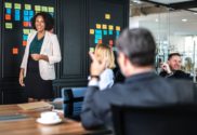 strategy - woman wearing white blazer standing in front of people at whiteboard - by rawpixel-755574-unsplash